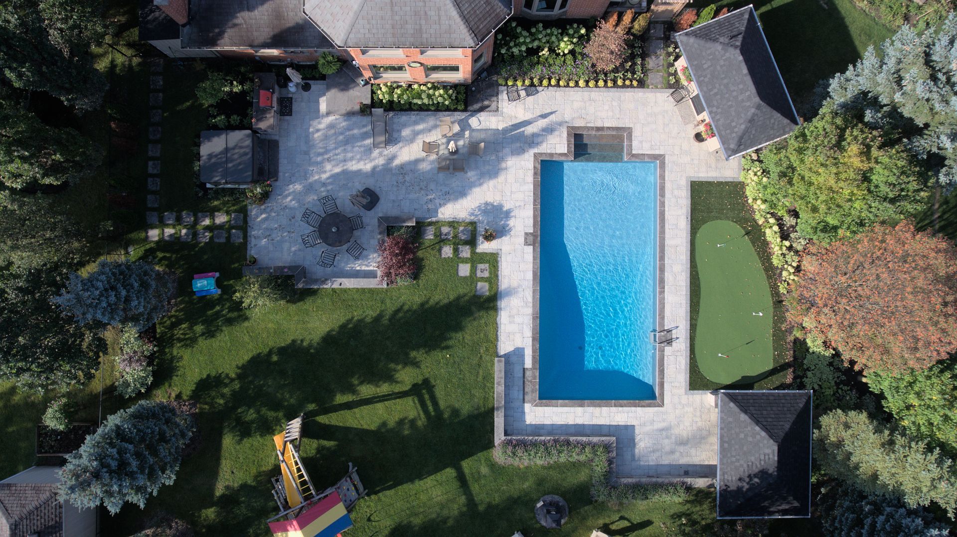 An aerial view of a large swimming pool in a backyard surrounded by trees.