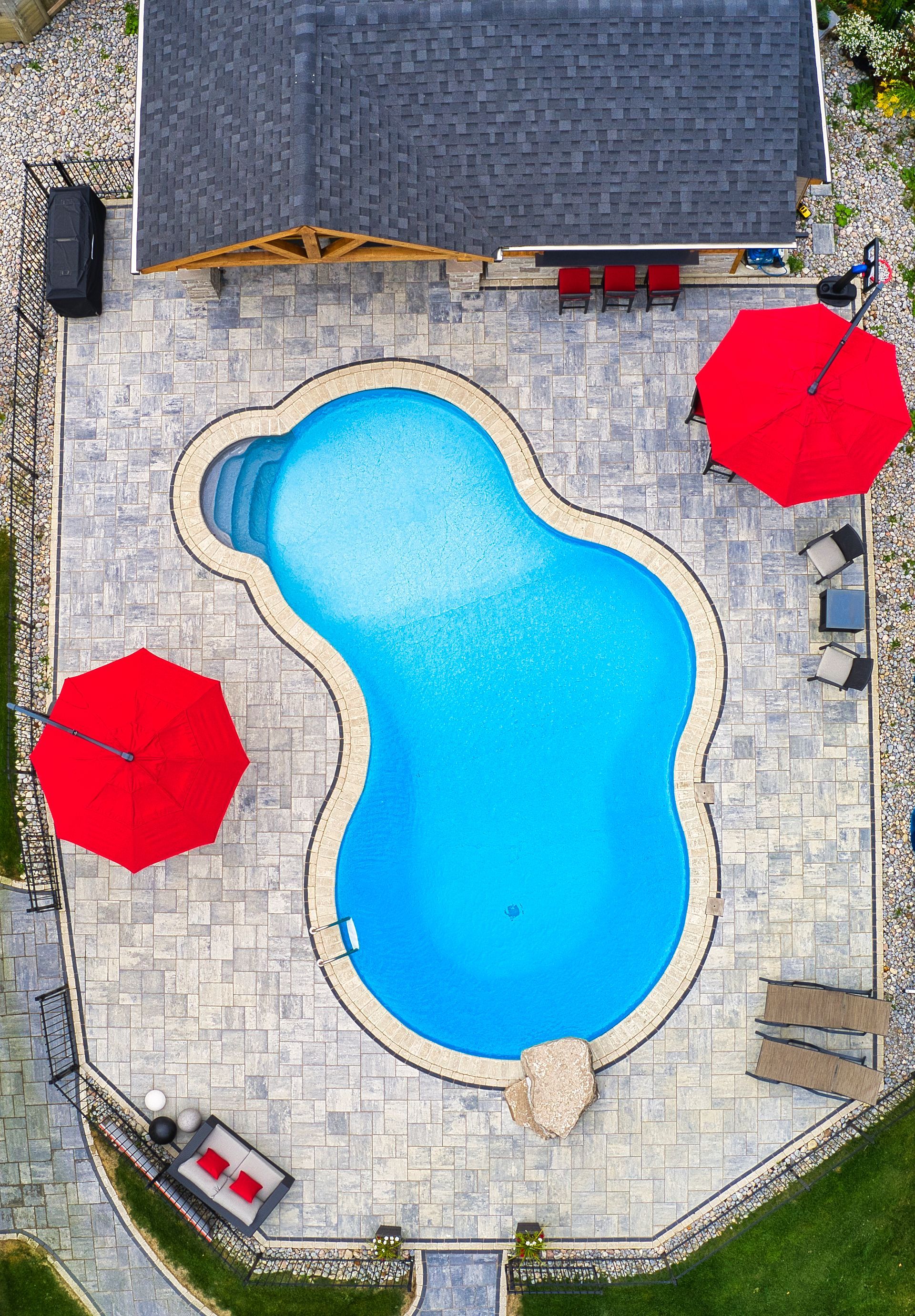 An aerial view of a large swimming pool with red umbrellas.