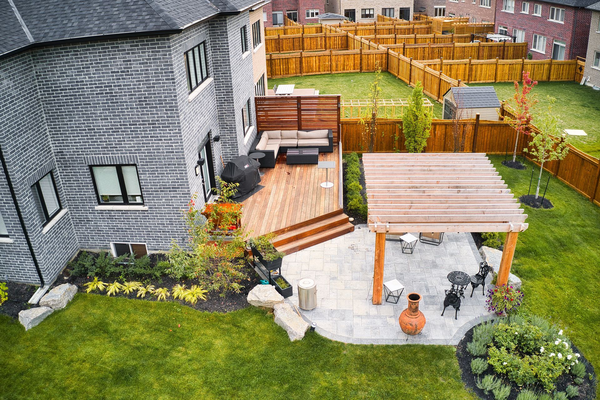 An aerial view of a backyard with a wooden deck and patio.