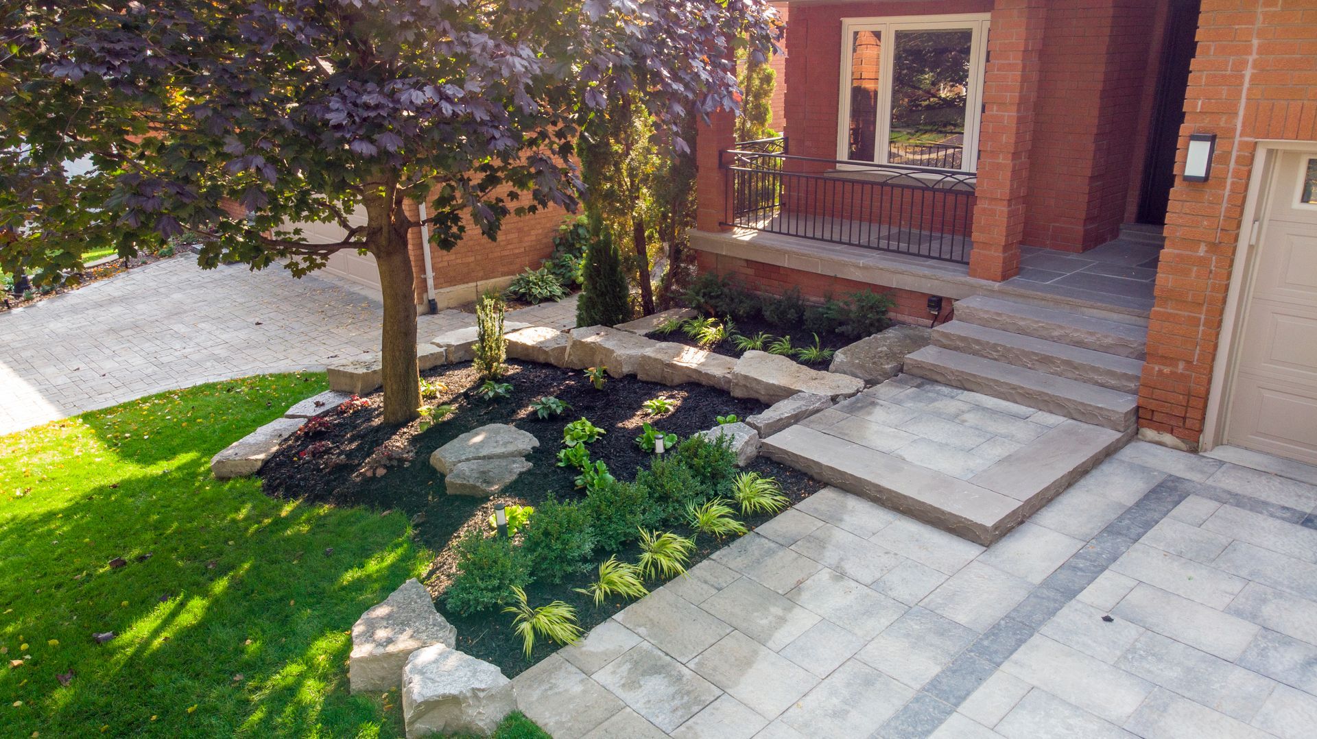 A brick house with a lush green lawn and a tree in front of it.