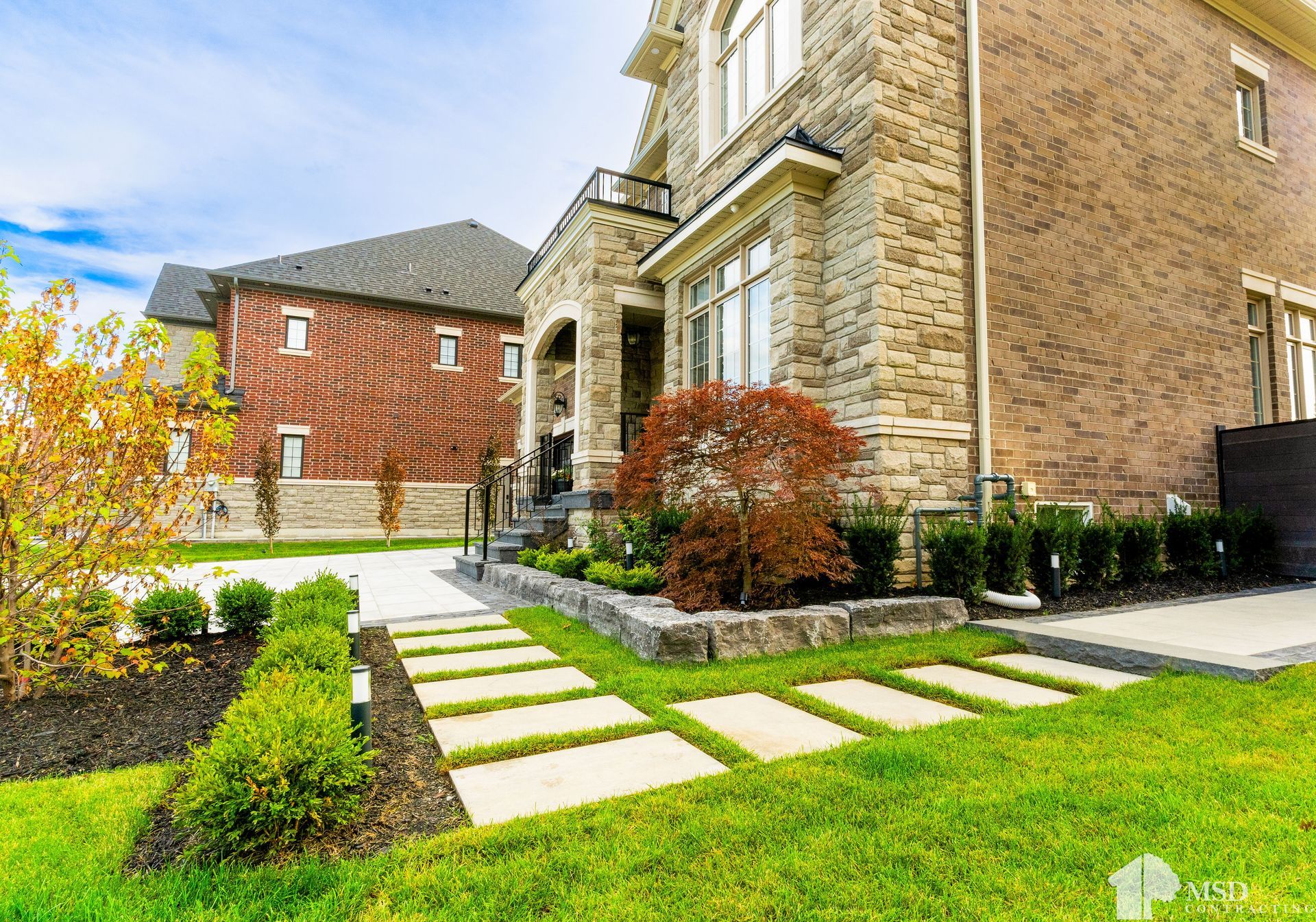 A large brick house with a lush green lawn in front of it.