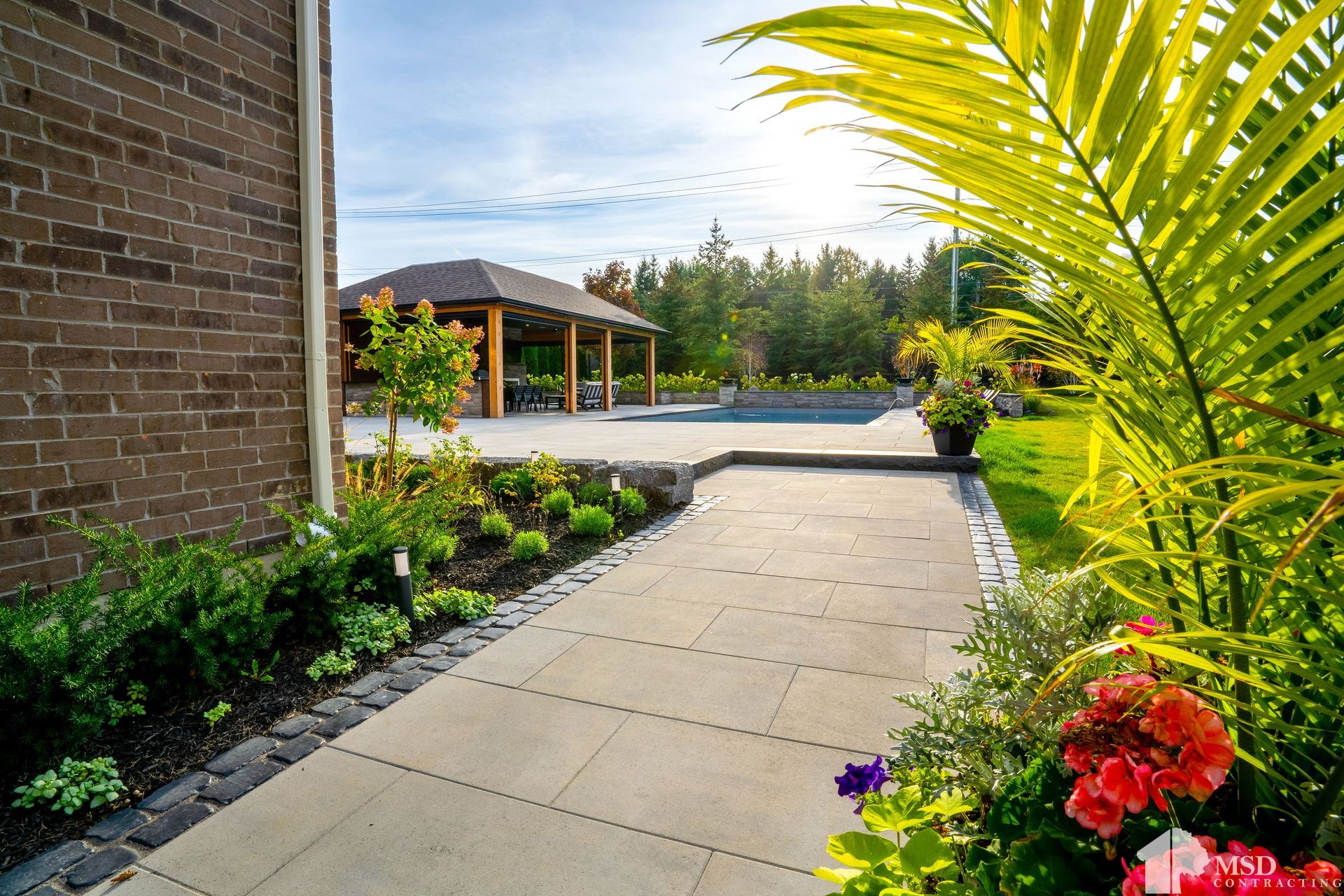 A walkway leading to a house with flowers and palm trees