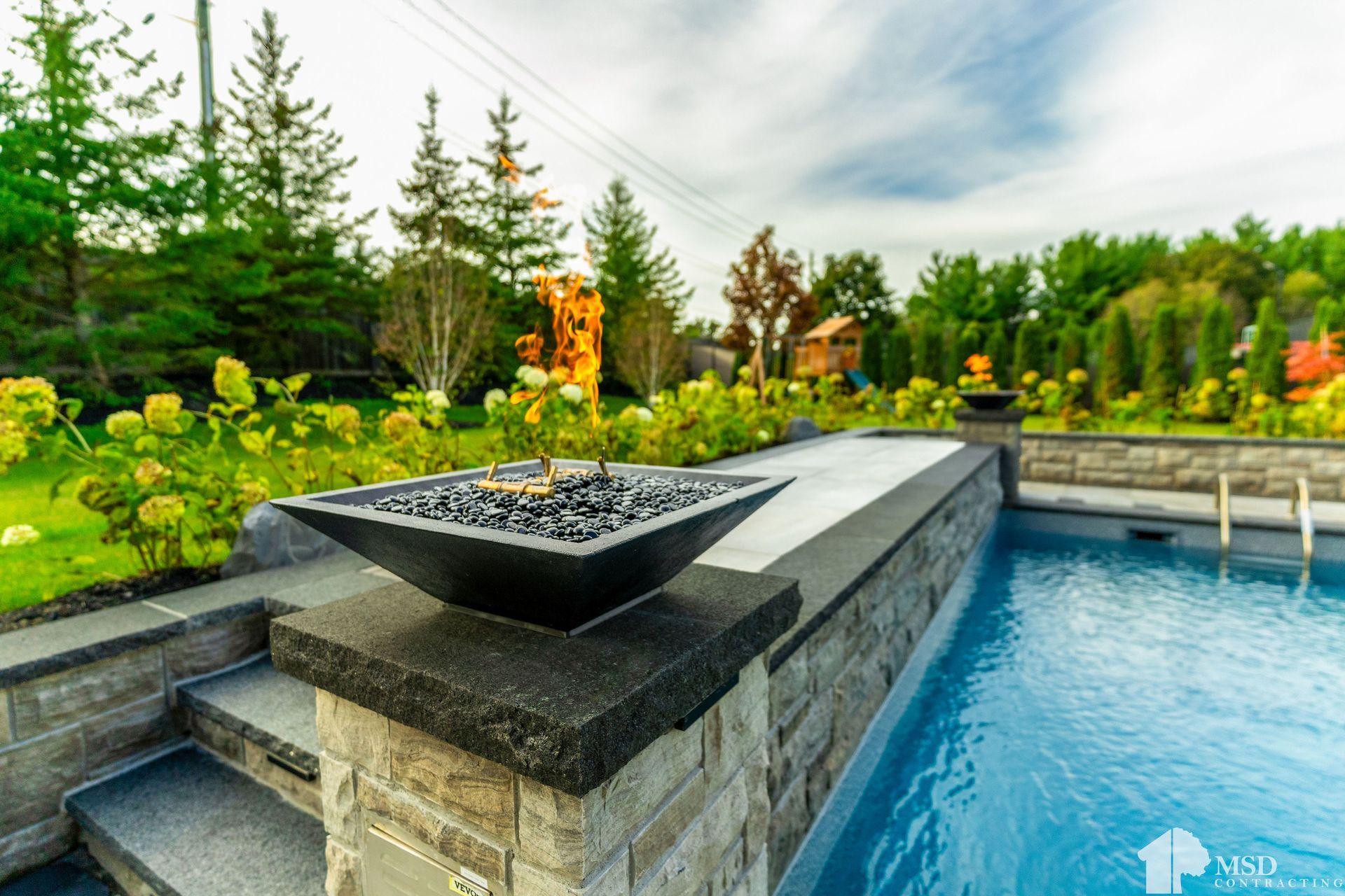 A swimming pool with a fire pit in the middle of it
