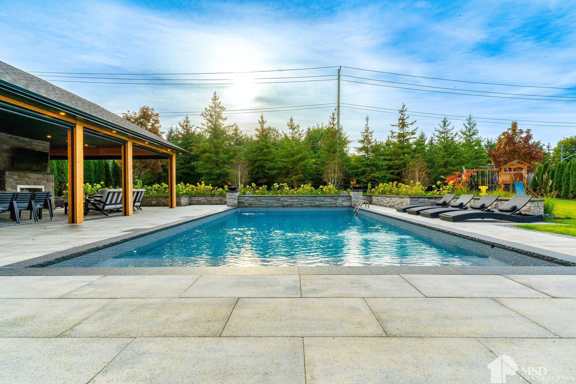 A large swimming pool surrounded by chairs and a gazebo in a backyard.