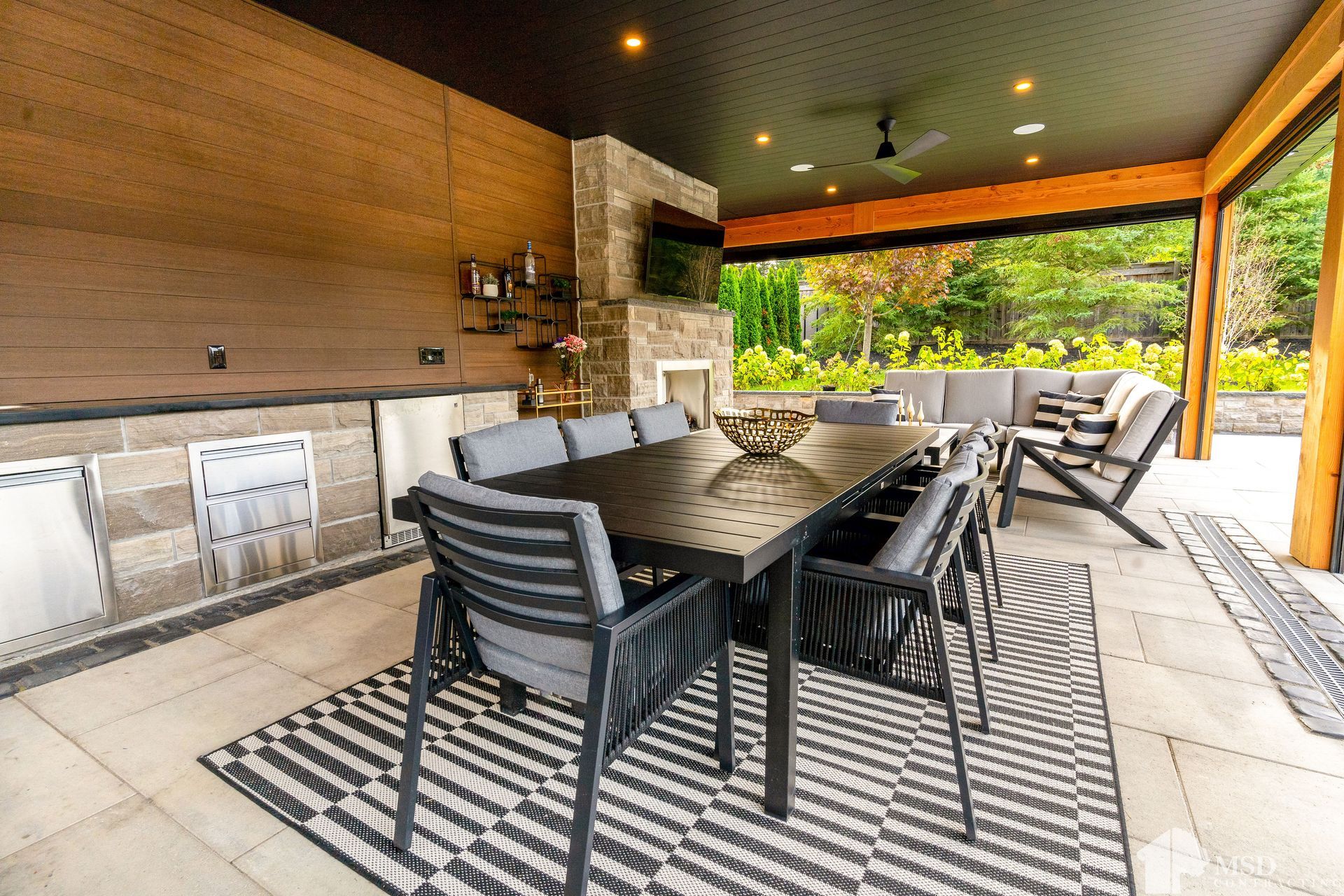 A patio with a table and chairs and a rug.