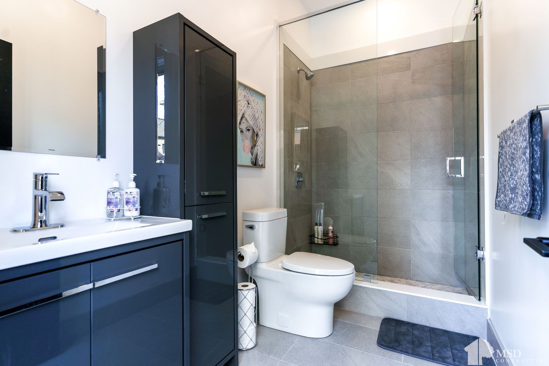 A bathroom with a toilet , sink , mirror and walk in shower.