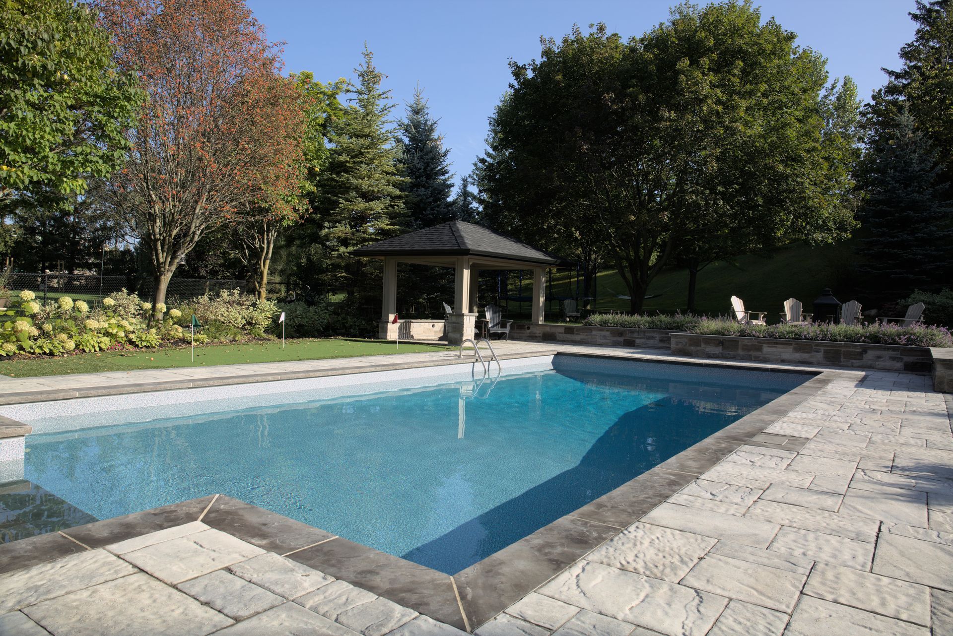 A large swimming pool with a gazebo in the background