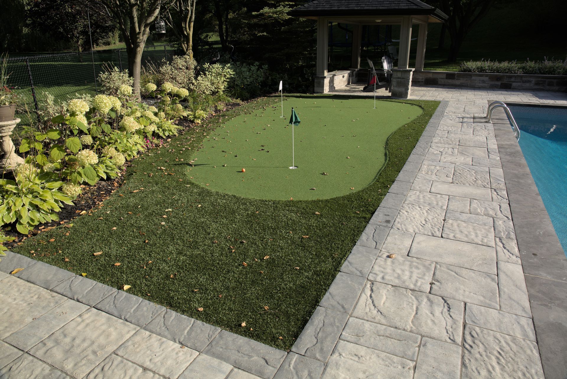 A putting green in a backyard next to a pool