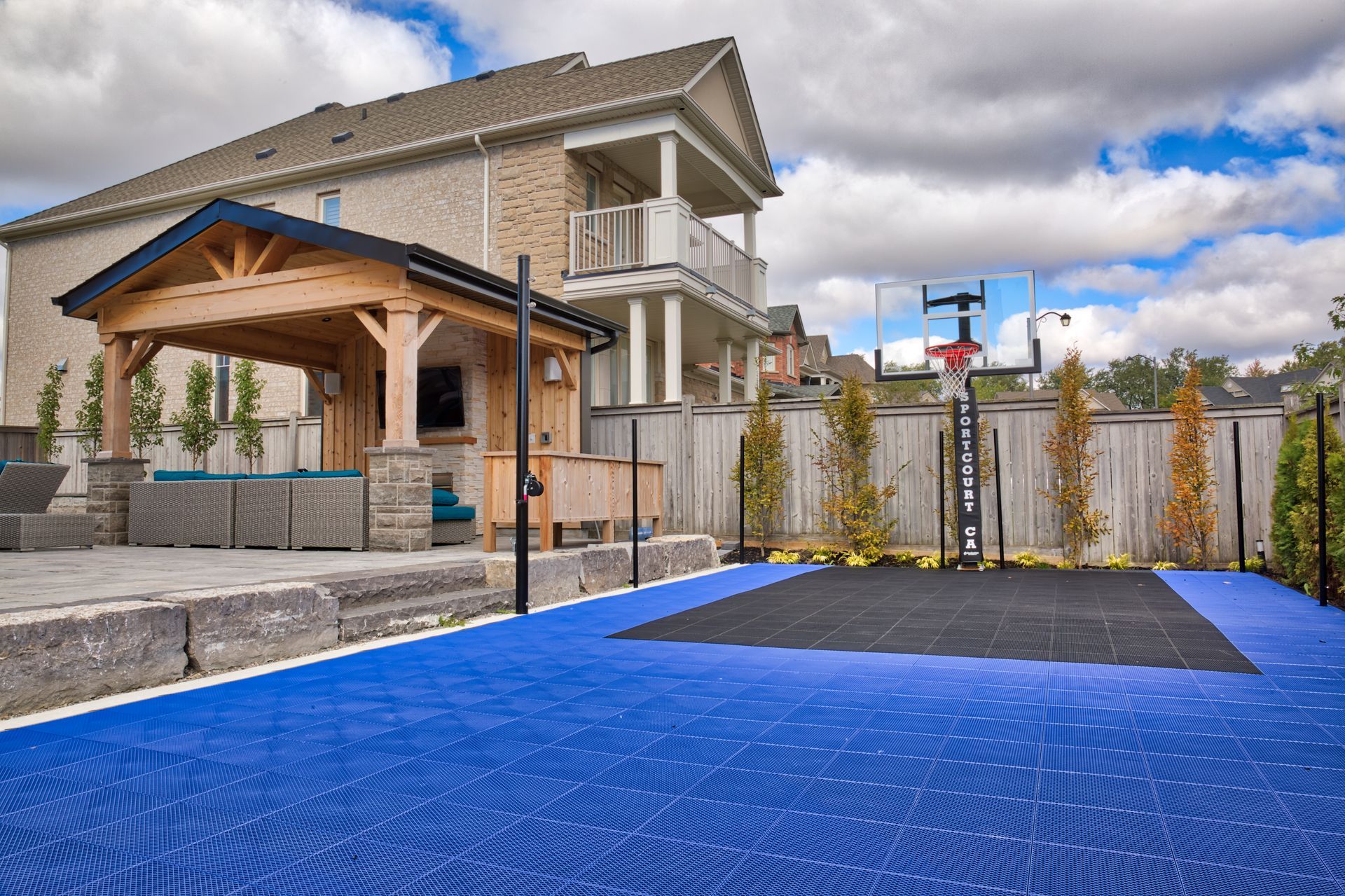 There is a basketball court in the backyard of a house.