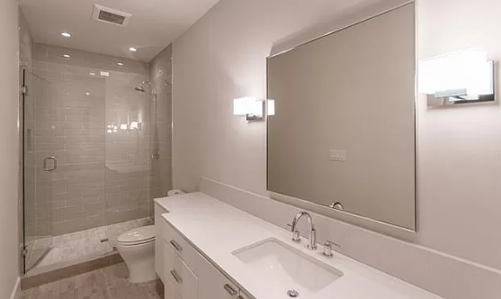 A bathroom with a sink , toilet , shower and mirror.