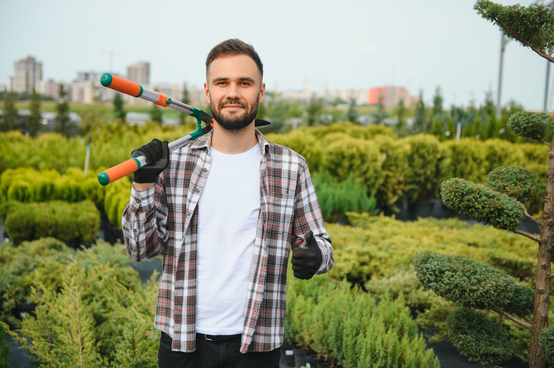 A man is holding a pair of scissors over his shoulder in a garden.
