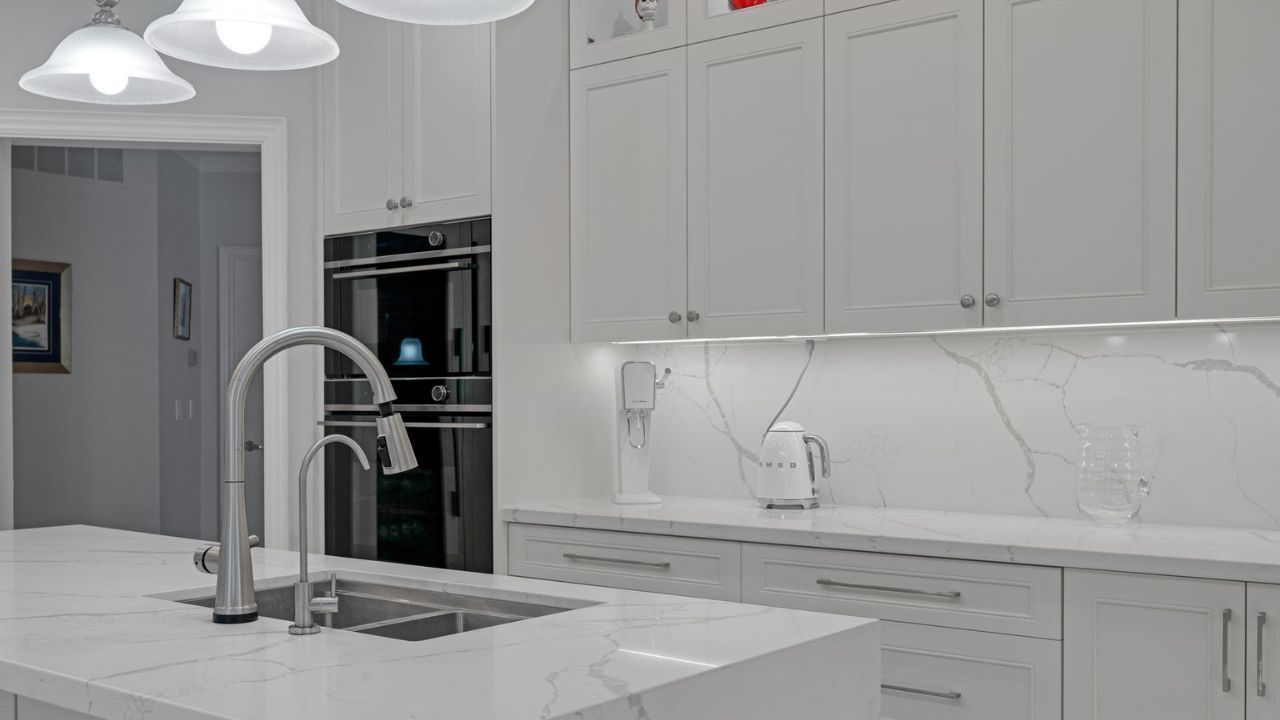 Modern kitchen with white cabinets, marble countertops, stainless steel faucet, and built-in oven - MSD Contracting Kitchens