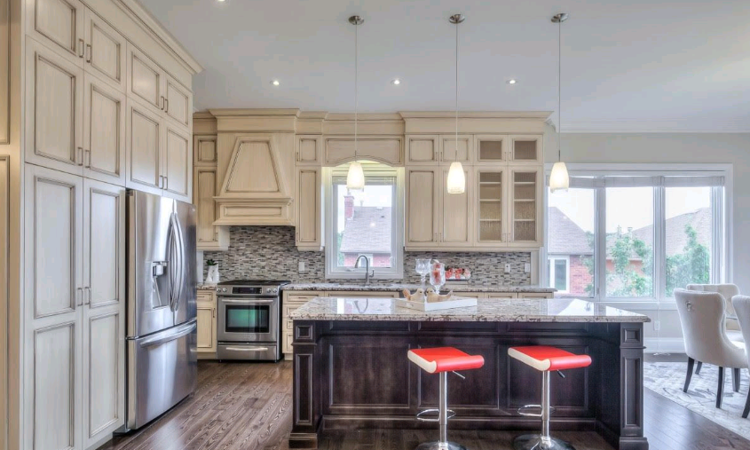 A kitchen with white cabinets , stainless steel appliances , granite counter tops and a large island.