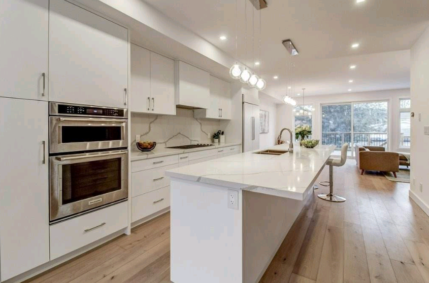 A kitchen with white cabinets and stainless steel appliances and a large island.