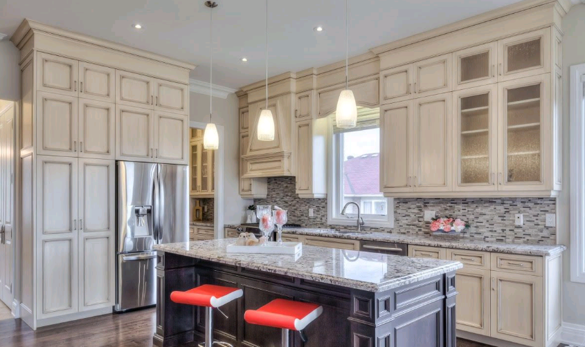 A kitchen with white cabinets , granite counter tops , stainless steel appliances and a large island.