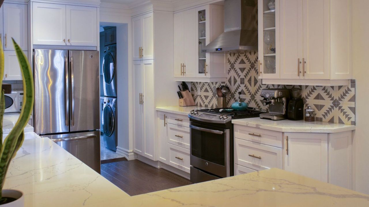 MSD Contracting Completed Kitchen Renovation with stainless steel appliances, dark floor, and patterned backsplash.