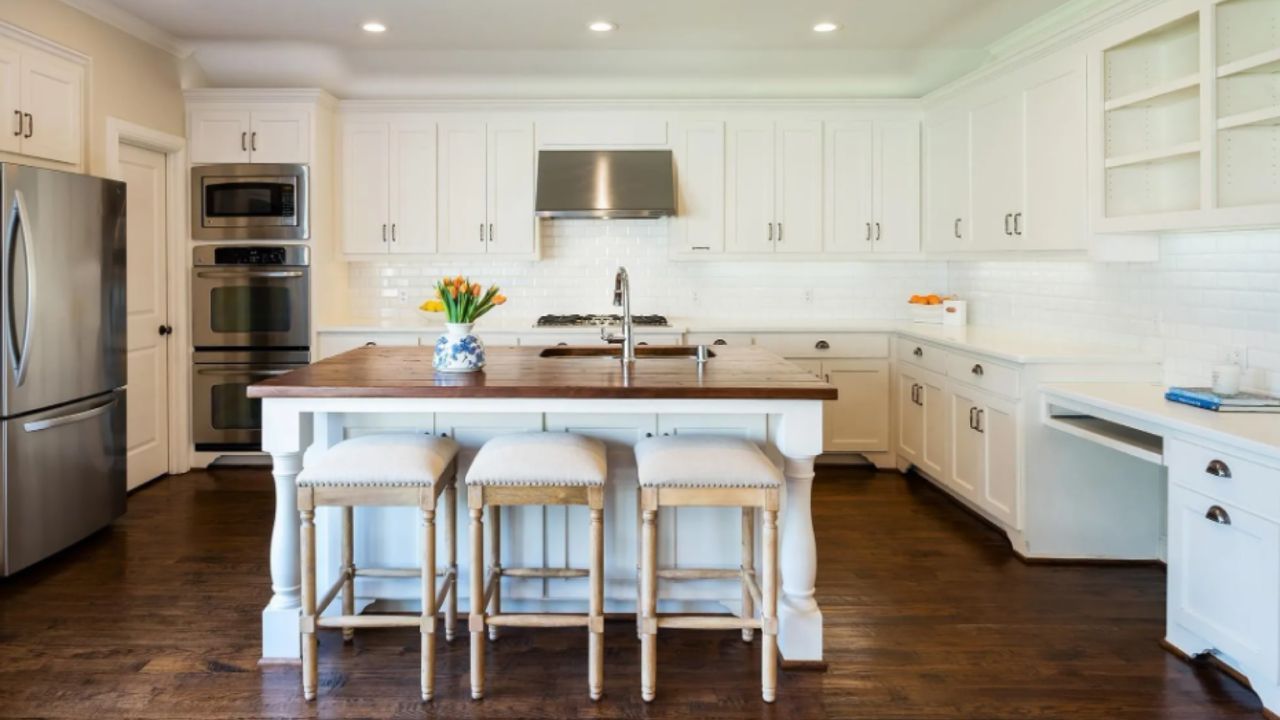 MSD Contracting finished Kitchen Renovation with dark wood floor, island with stools, stainless steel appliances.