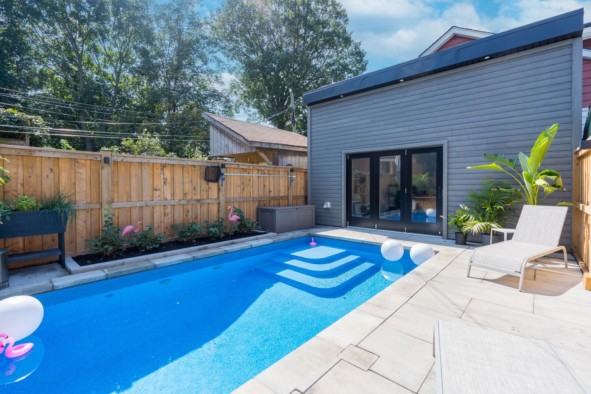 There is a large swimming pool in the backyard of a house.