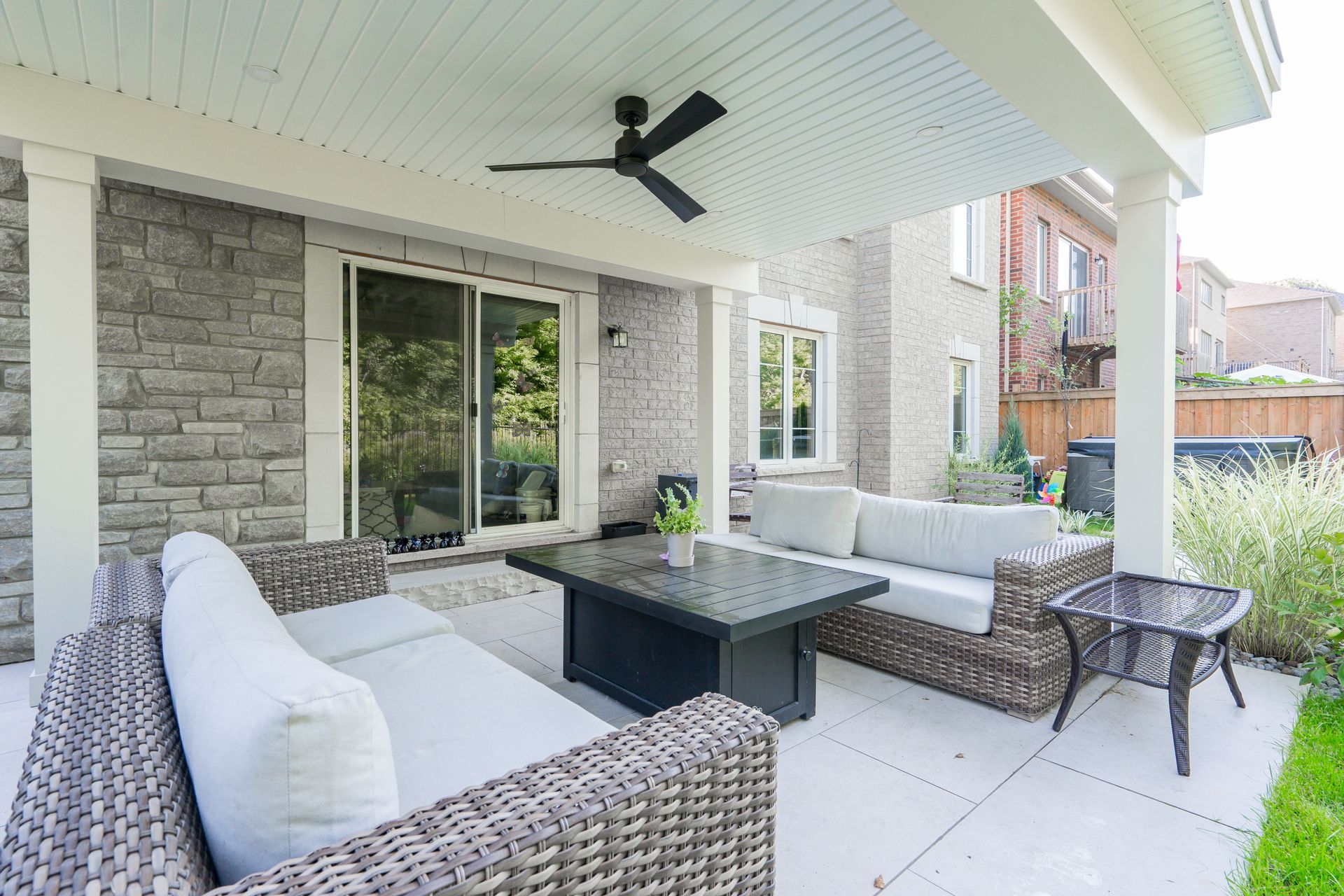 A patio with a couch , table , and ceiling fan.