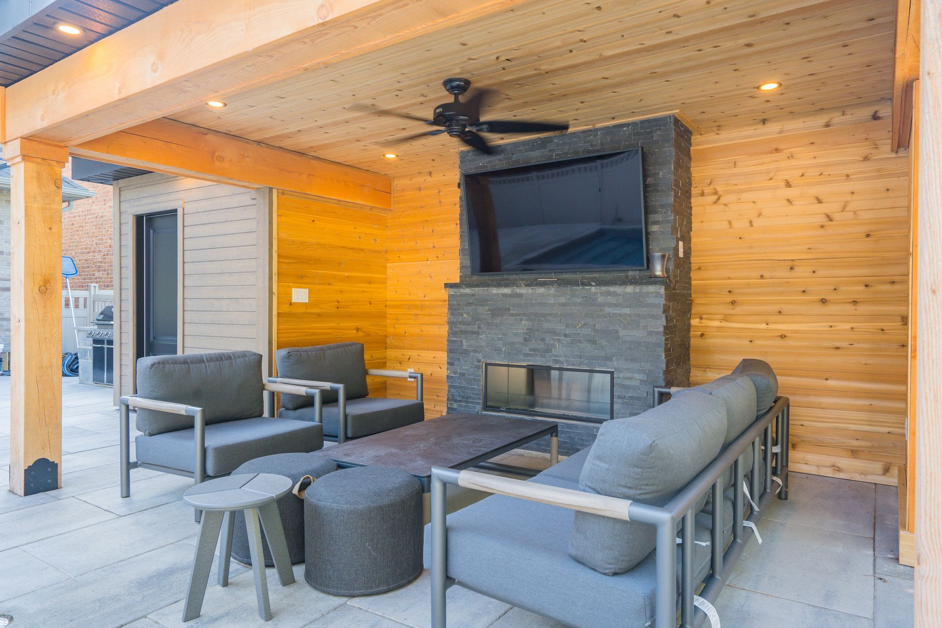 A patio with a fireplace and a flat screen tv.