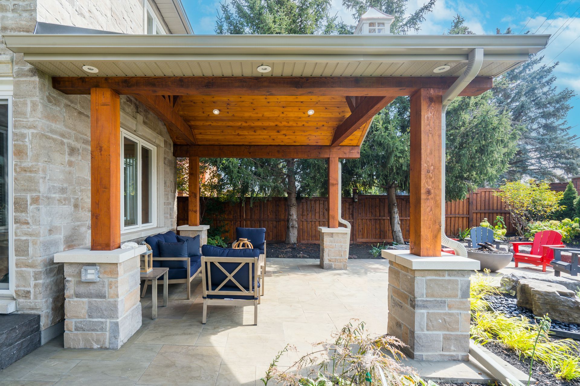 A patio with a wooden pergola and a fire pit in the backyard of a house.