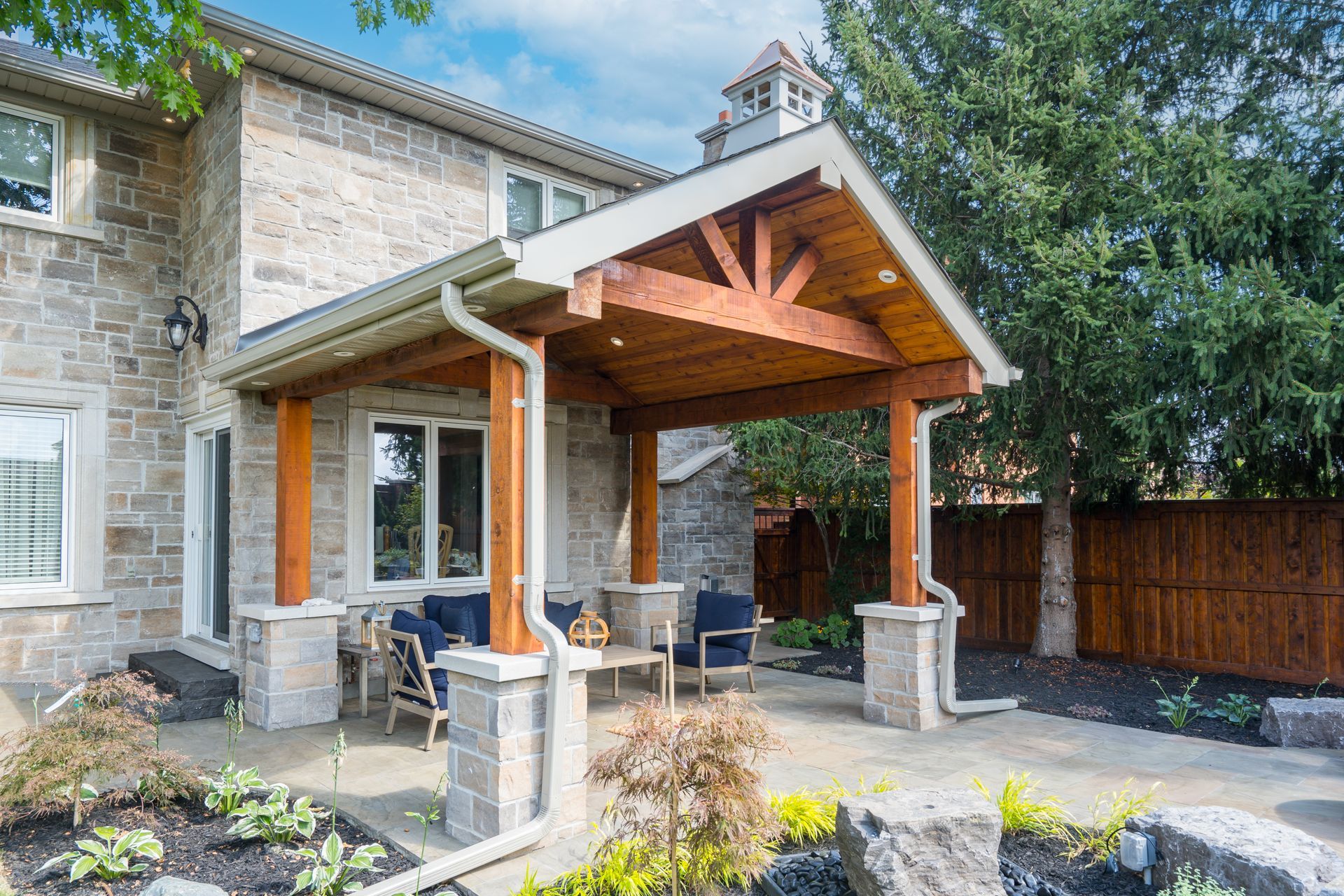 A large stone house with a wooden porch and patio area.