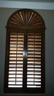 A window with arched wooden shutters in a room.