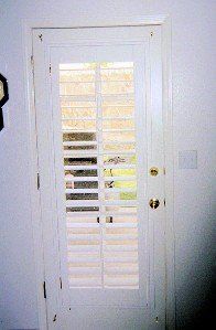 A white door with shutters on it is open to a window.