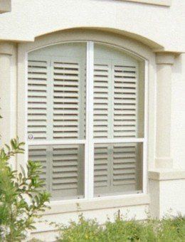 A window with arched shutters on a white building