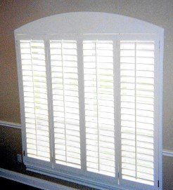 A window with white shutters on it in a room.