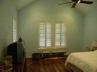 A bedroom with a bed , television , and ceiling fan.