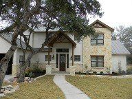 A large white house with a stone roof and a tree in front of it.