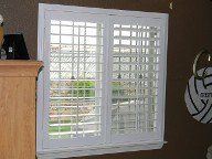 A bedroom window with white shutters and a volleyball sign on the wall.