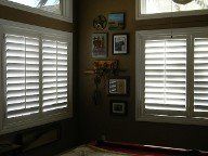 A bedroom with shutters on the windows and pictures on the wall.