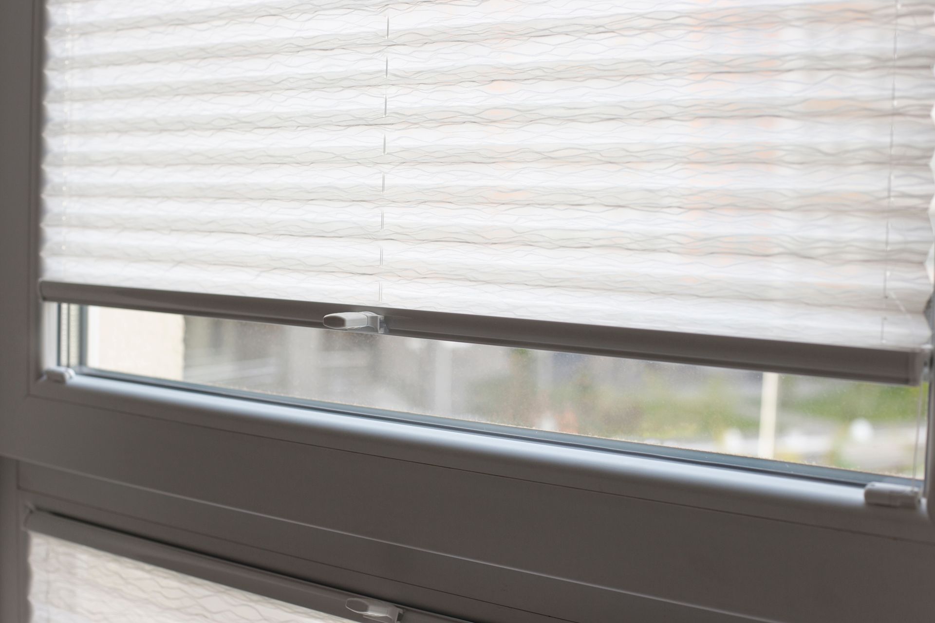 A close up of a window with a pleated blind on it.