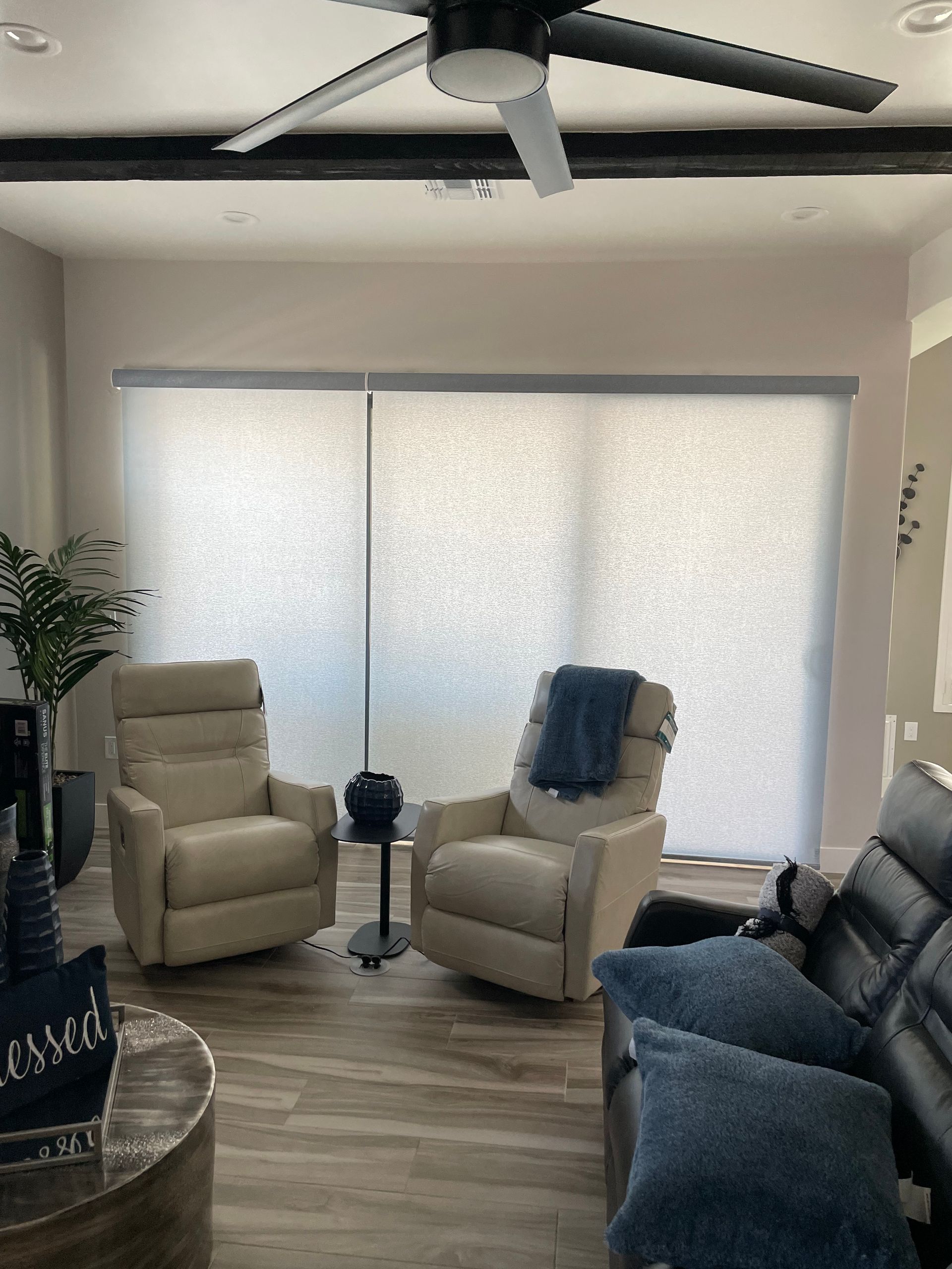 A living room with two recliner chairs , a couch , and a ceiling fan.