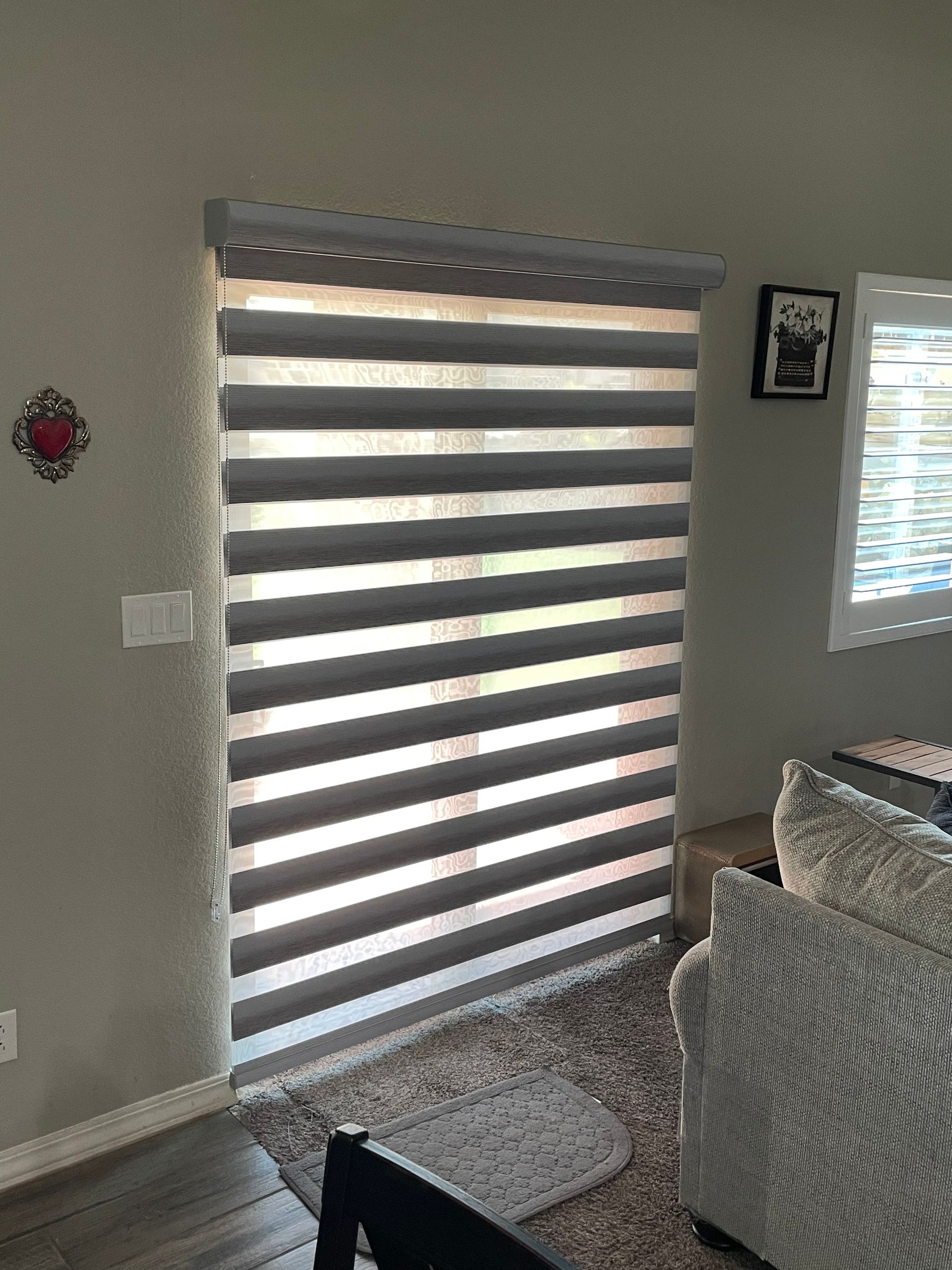 A living room with a sliding glass door and blinds on it.