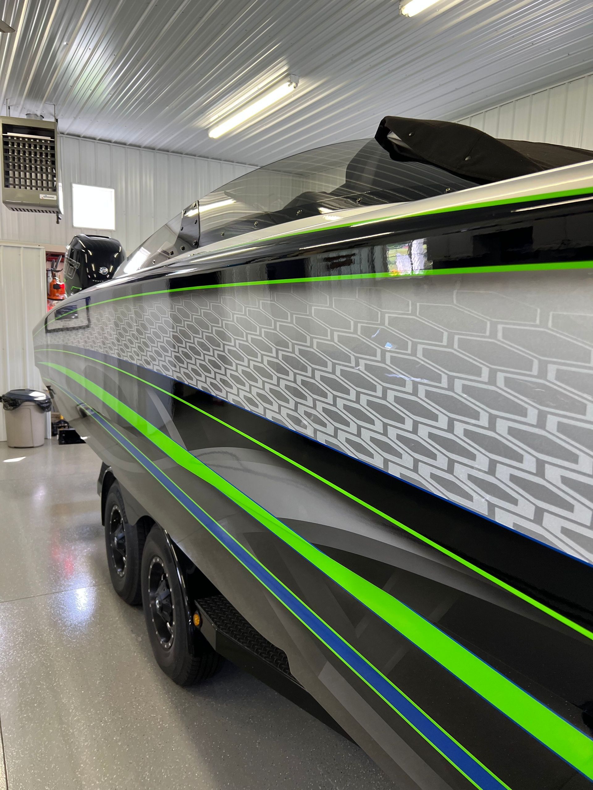 A black and green boat is parked in a garage.