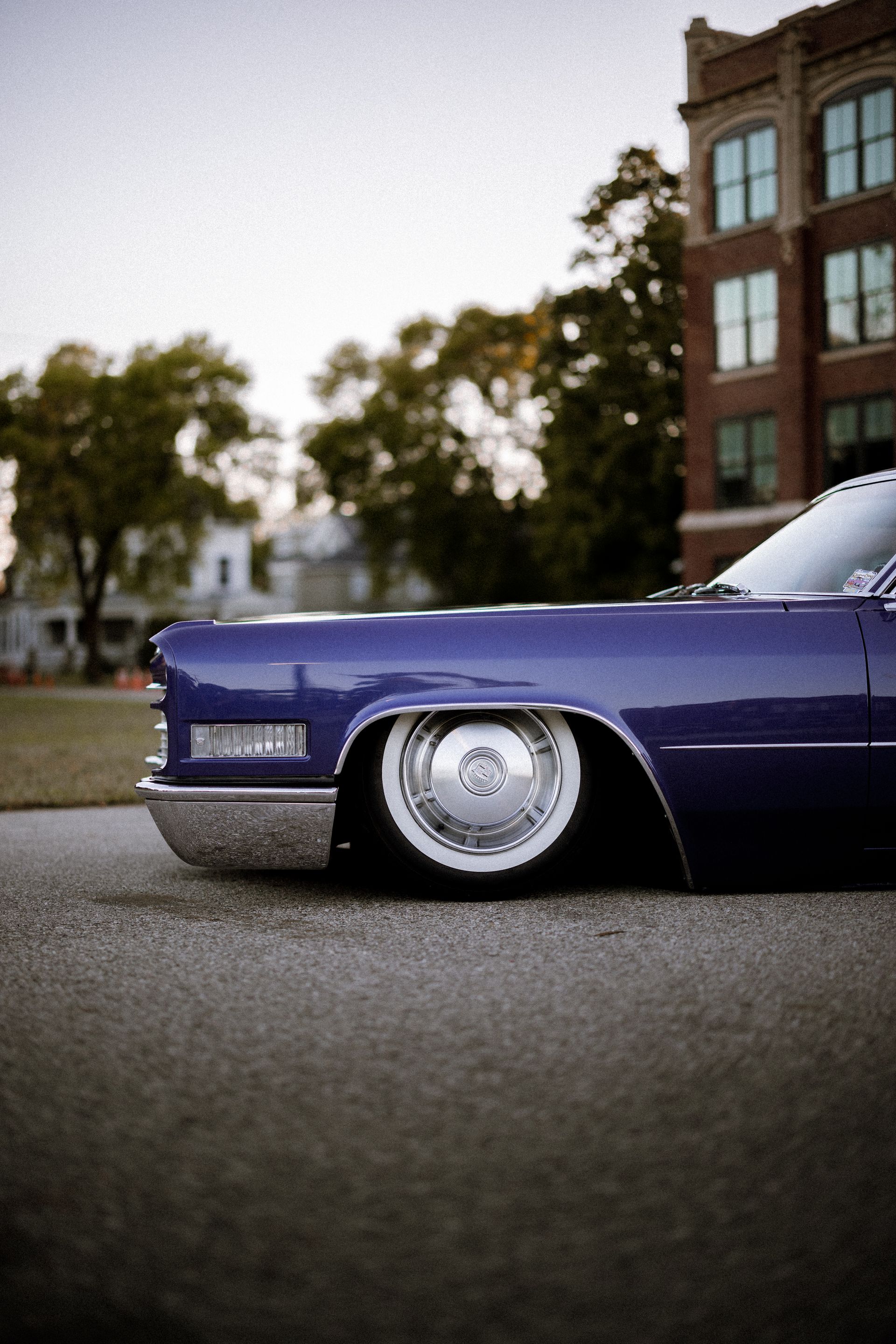 A purple car is parked on the side of the road in front of a building.