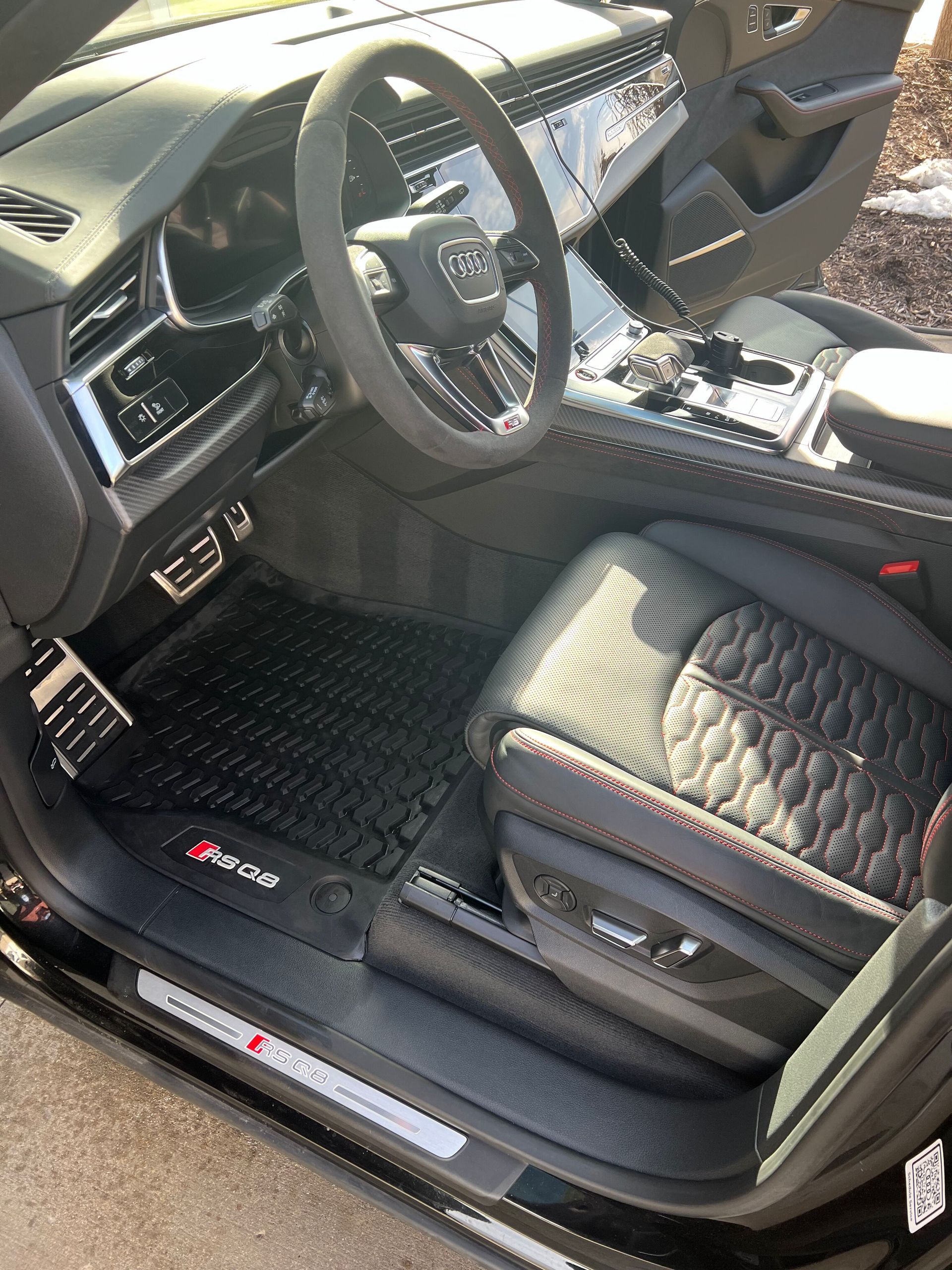 The interior of a black audi rs q7 is shown with the door open.