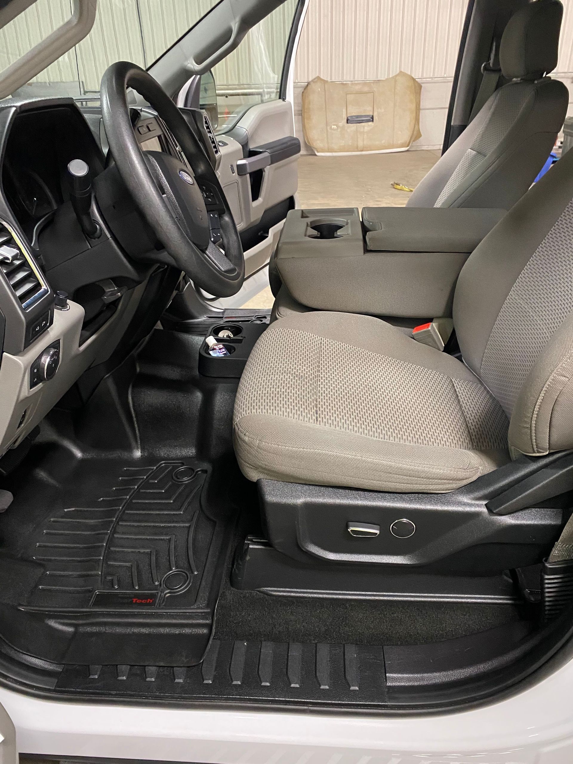 The inside of a white car with a steering wheel and seats.