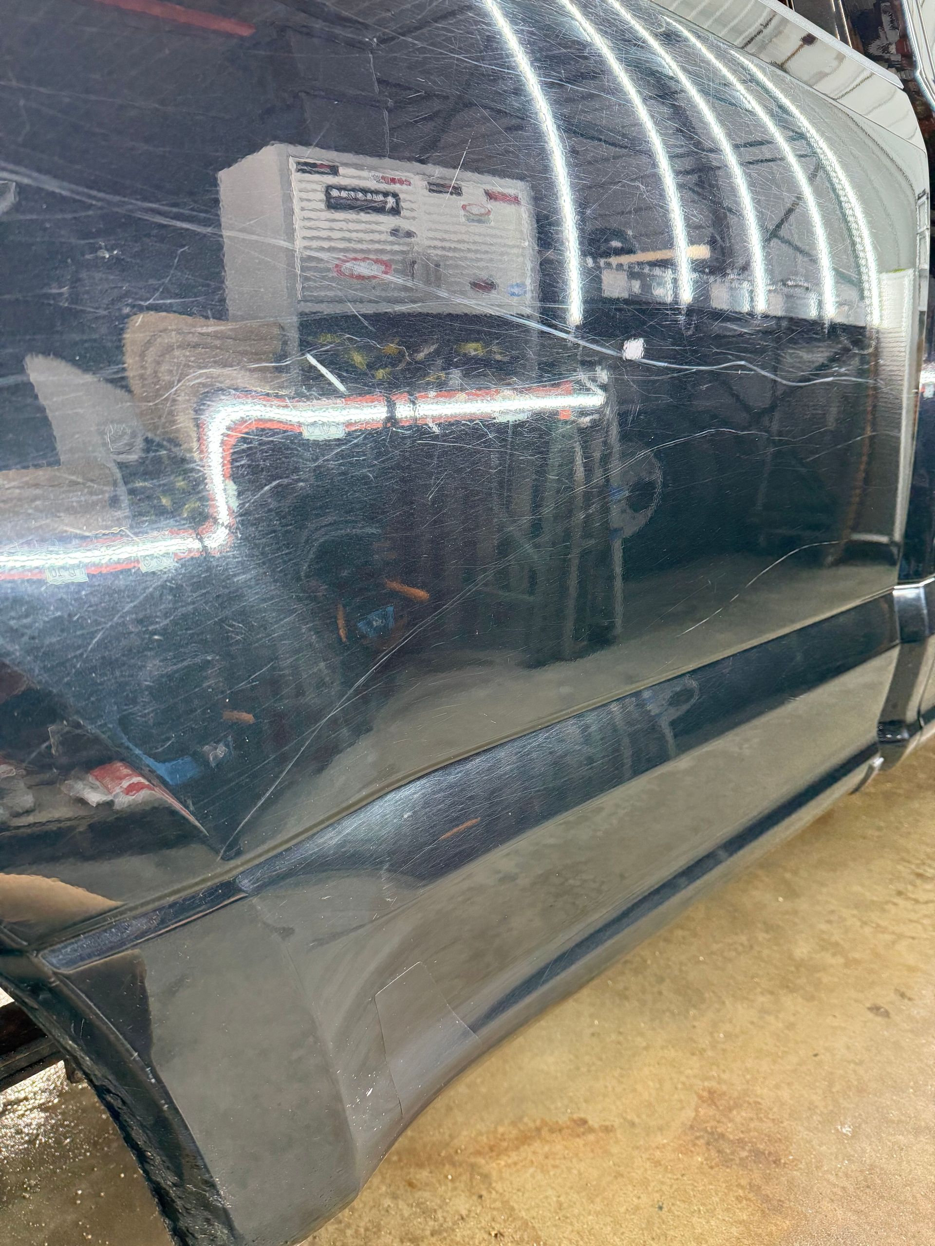 A black car is parked in a garage with a lot of scratches on it.