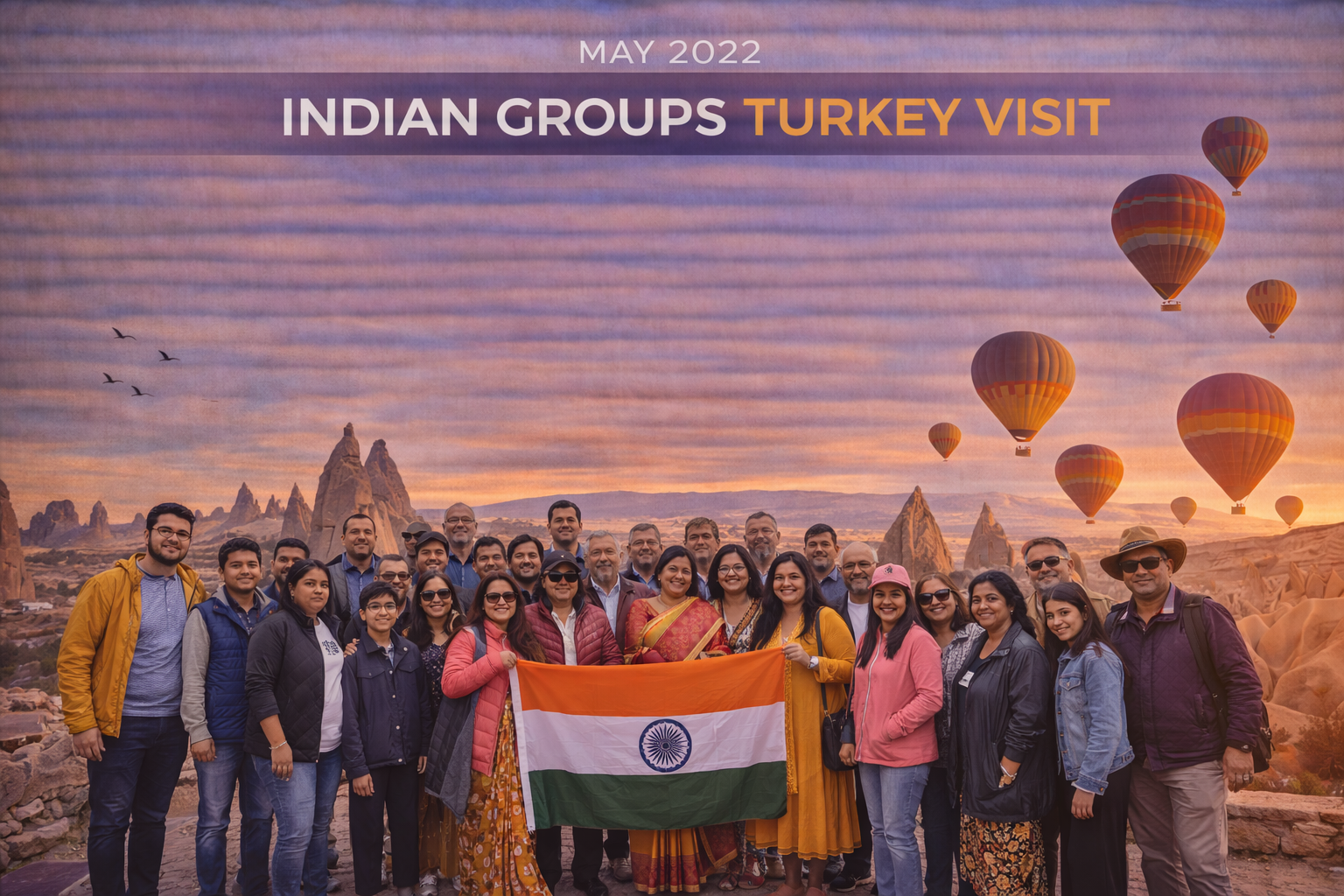 Group of people holding Indian flag, posing in Cappadocia, Turkey, with hot air balloons at sunrise.