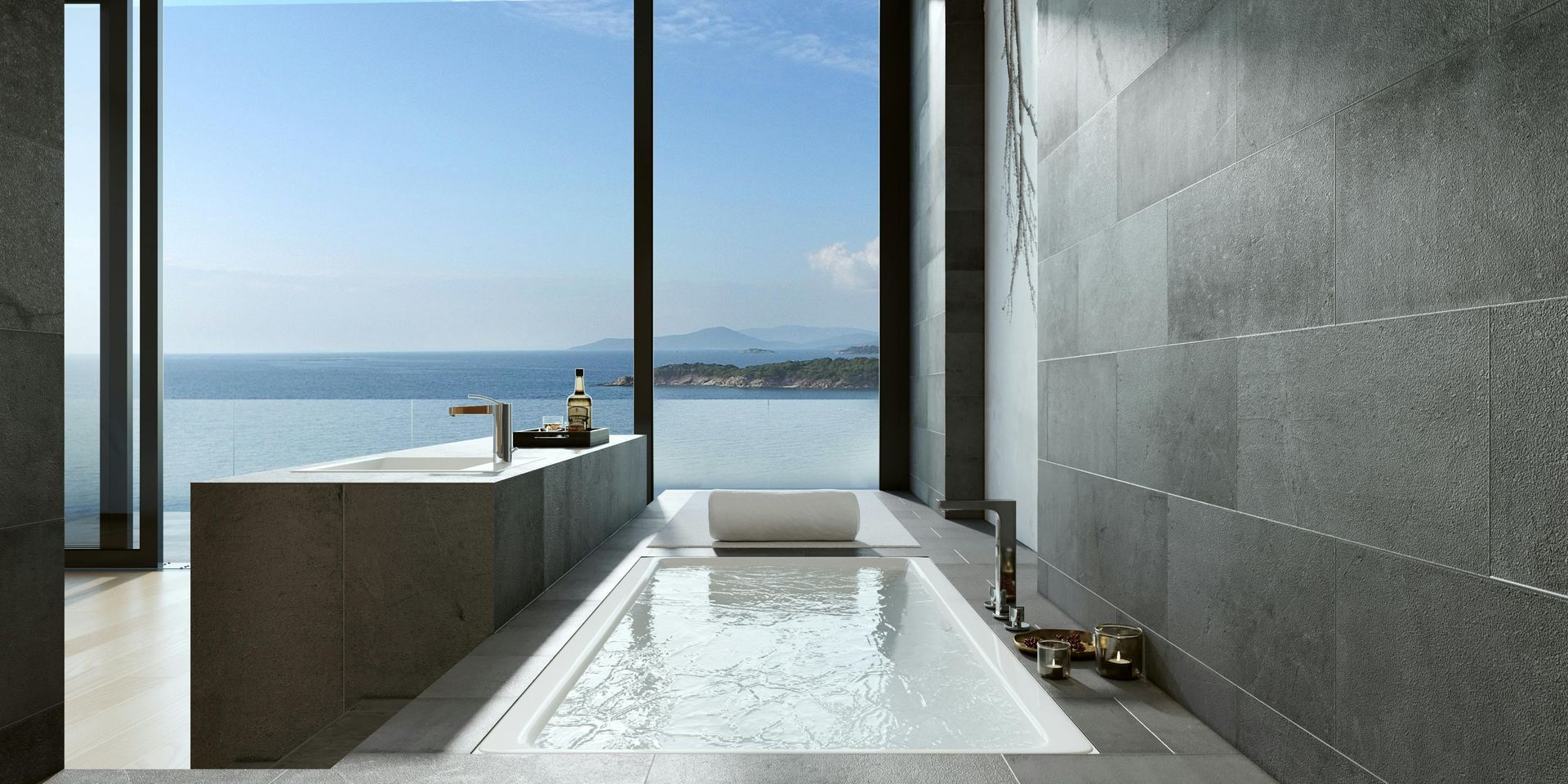 Luxury bathroom with a large window overlooking the ocean; gray stone walls and a modern bathtub.