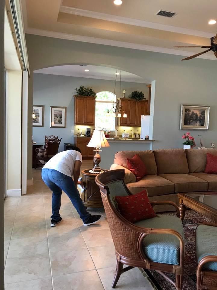A woman is cleaning the floor of a living room.