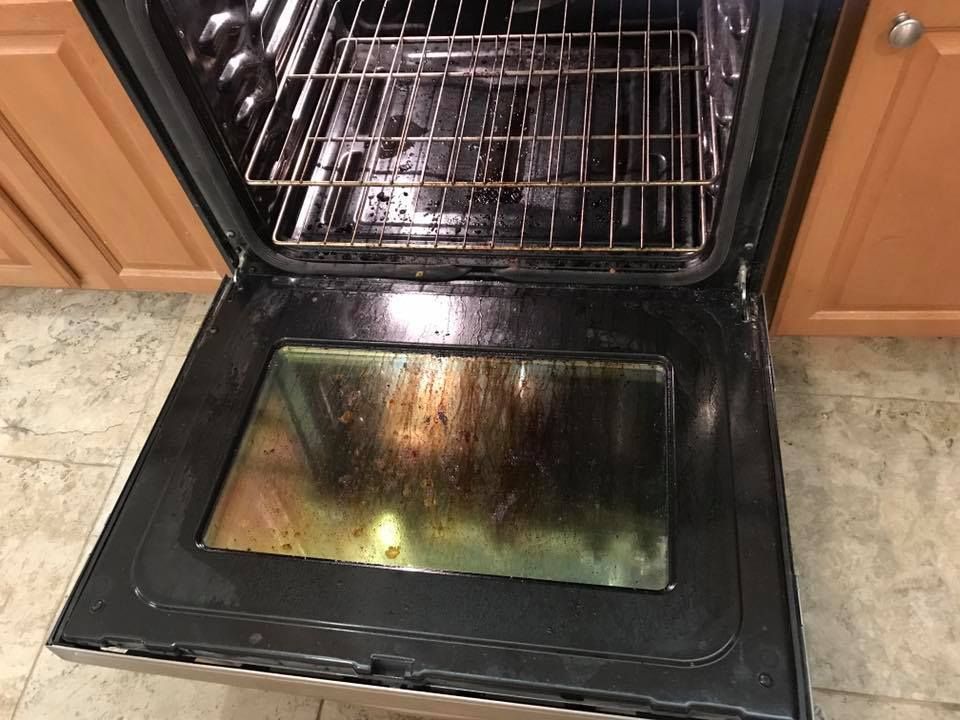 A dirty oven with the door open in a kitchen.