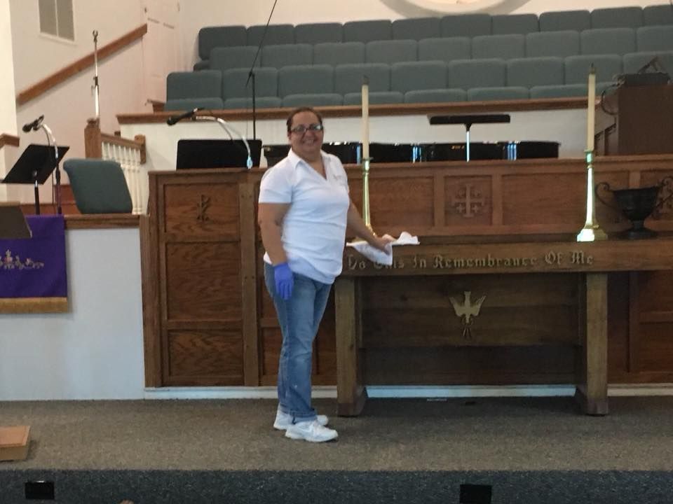 A woman is standing in front of a wooden altar with the word jesus on it