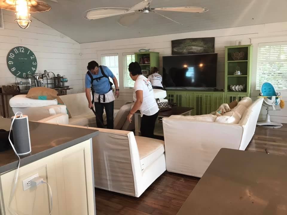 Two men are cleaning a living room with a vacuum cleaner.