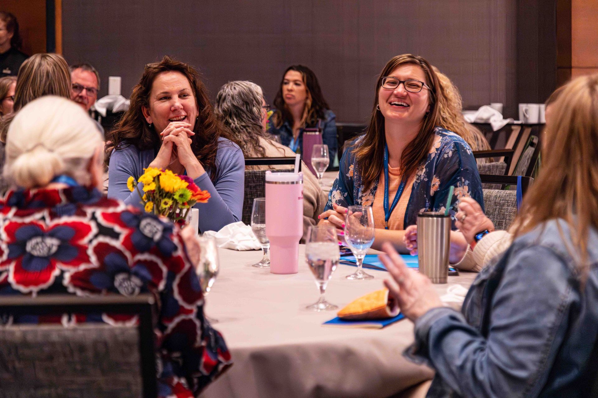 A group of women are sitting at a table talking to each other.