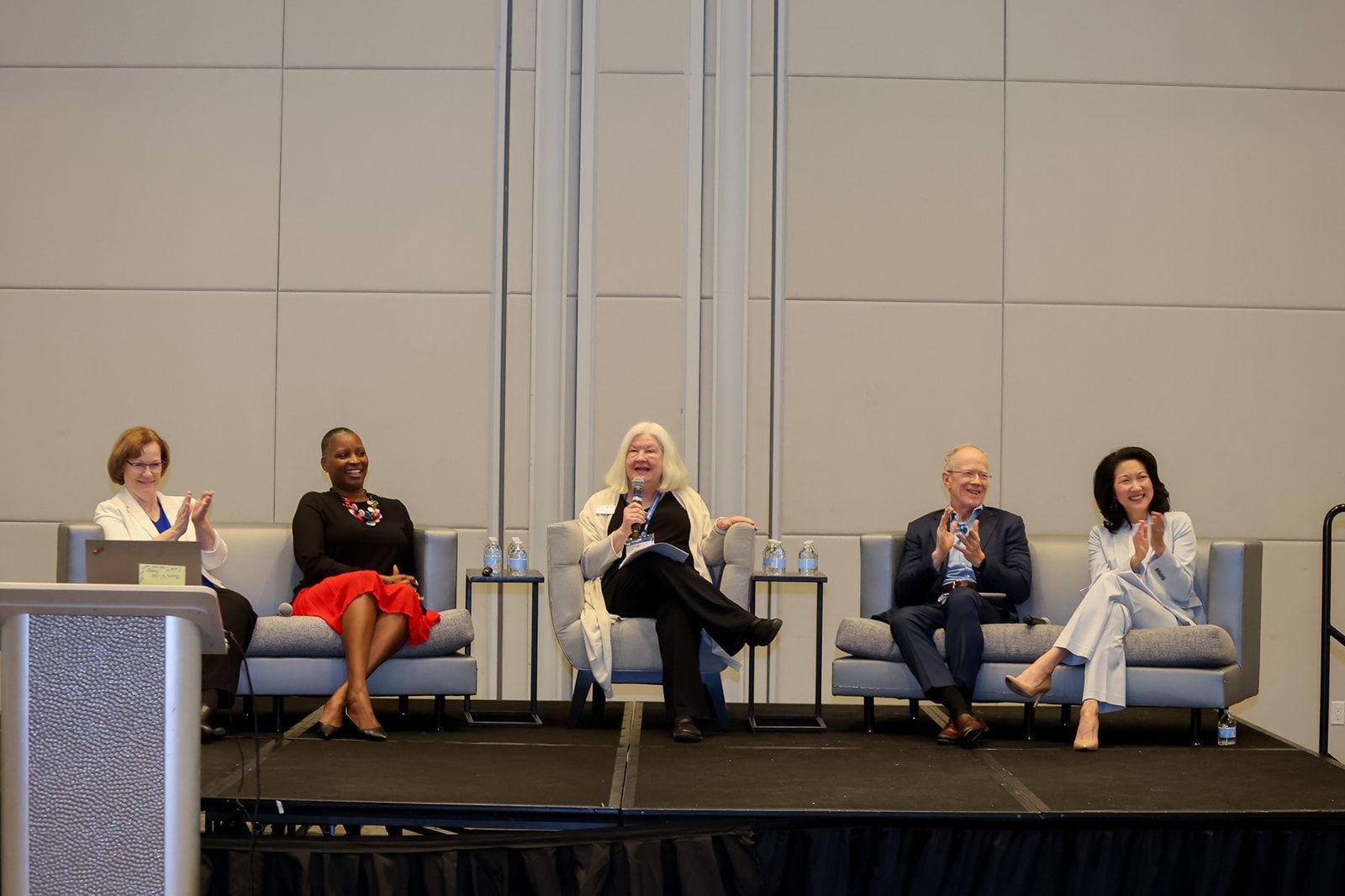 A group of people are sitting on couches on a stage.